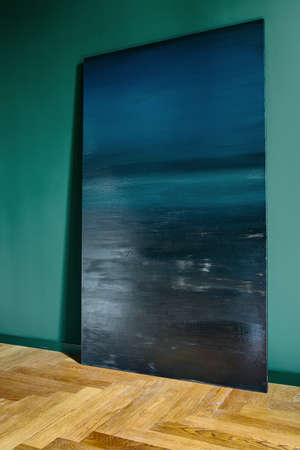 Big blue picture which leans on the turquoise wall. There is a parquet on the floor. Indoors. Vertical.の写真素材