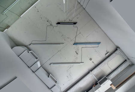 Ceiling with the lamps and communications in the interior with gray walls in a loft style. Indoors. Horizontal.の写真素材