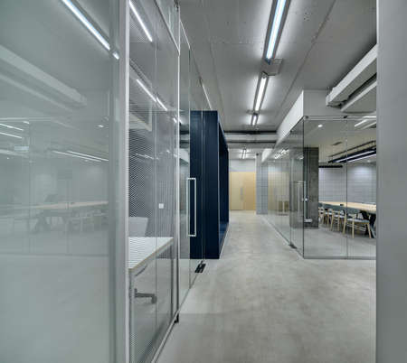 Corridor between work zones in the office in a loft style. Zones are fenced with mesh, glass and...