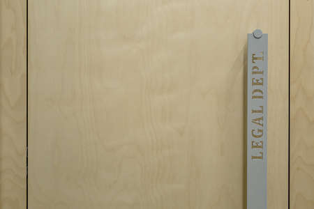 Macro photo of the door handle. On the handle there is an inscription Legal Dept. Door is wooden. Horizontal.の写真素材