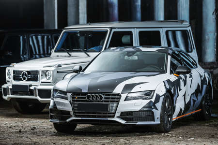 Kiev, Ukraine - 14 May 2014: Audi S7 and white Mercedes G55 Gelandewagen AMG tuning sport-cars. Audi colored in white, black, gray colors with patterns and orange stripes. Editorial photo.のeditorial素材