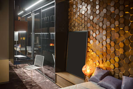 Modern bedroom with a carpet on the floor and a wooden wall textured with hexagons. There is a...