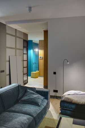 Luminous interior in a modern style with gray and blue walls. There is glowing lamps, sofa and a...