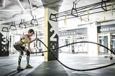 Girl does exercise with fitness rope in gymの写真素材