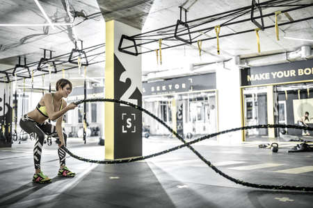Girl does exercise with fitness rope in gymの写真素材