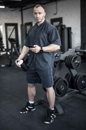 Muscular man has pause in gymの写真素材