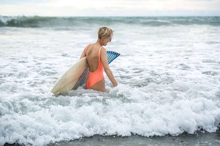 Blonde with surfboard on beachの写真素材