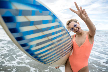 Blonde with surfboard on beachの写真素材