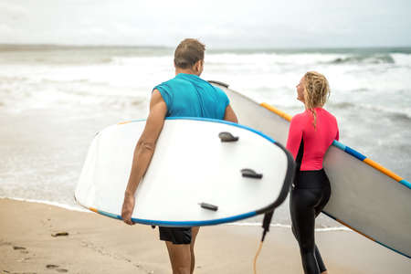 Couple of surfers on oceans shoreの写真素材