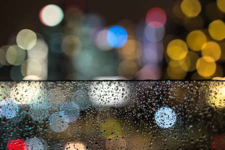 View through the wet glass on the blurry sources of the city lights. Closeup photo. Horizontal.の写真素材