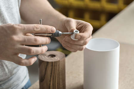 Constructor is using a t-wrench on the metal white detail in the workshop. On the table there are...