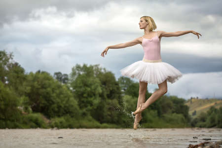 Ballerina jumping above riverの写真素材