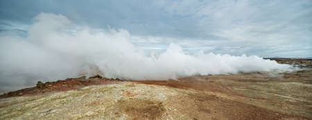 Geothermal geyser is steaming on the background of the cloudy sky in Iceland. Panoramic. Horizontal.の写真素材