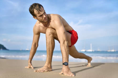 Tanned guy in red shorts on beach. Daylight shooting.の写真素材