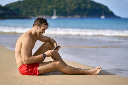 Tanned guy in red shorts on beach. Daylight shooting.