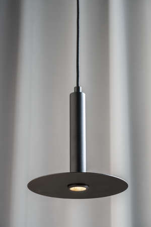 Black metallic lamp hanging on gray curtain backgroundの写真素材