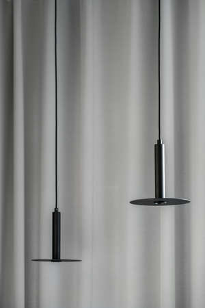 Black metallic lamps hanging on gray curtain backgroundの写真素材