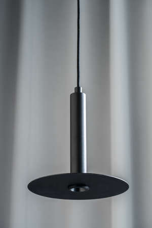 Black metallic lamp hanging on gray curtain backgroundの写真素材