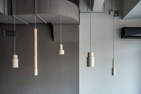 Different metallic-wooden lamps hanging on gray wall backgroundの写真素材