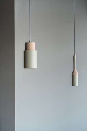 Different metallic-wooden lamps hanging on gray wall backgroundの写真素材