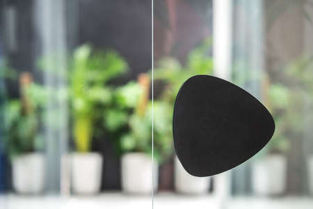 Closeup low aperture photo of the glass door with a black handle on the background of the green plants in the big pots. Horizontal.の写真素材