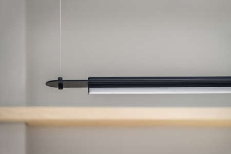 Black metallic lamp is hanging on the gray wall background indoors. Closeup low aperture photo. Horizontal.の写真素材