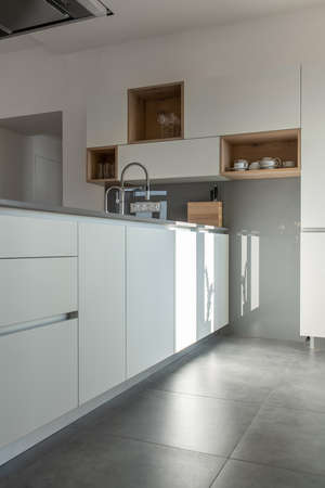 Sunny modern kitchen with white walls and tiled floorの写真素材
