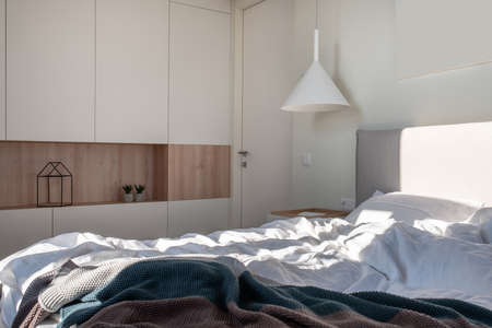 Sunny modern bedroom with white walls and hanging lampの写真素材