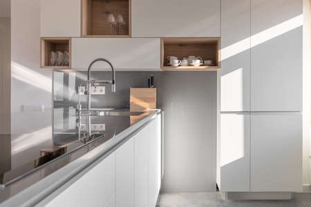 Sunny modern kitchen with white walls and tiled floorの写真素材