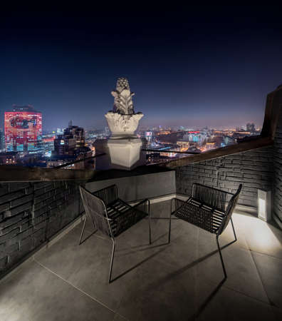 Small terrace with brick walls on night cityscape backgroundの写真素材
