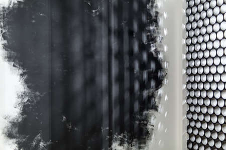 White and black wall with shadows on it and a gray partition made of short pipesの写真素材