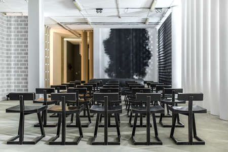 lot of the black wooden chairs between the white glowing columnsの写真素材
