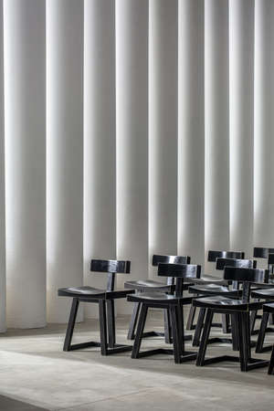Many black wooden chairs on the background of the luminous white columnsの写真素材