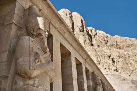 Pharaoh statues on the facade of the ancient building on the blue sky background in Luxor in Egypt. It is sunny. Horizontal.の写真素材
