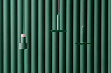 Three different metal dark green lamps are hanging on the same color folded wall background indoors. One of them has a wooden part. Closeup horizontal photo.の写真素材