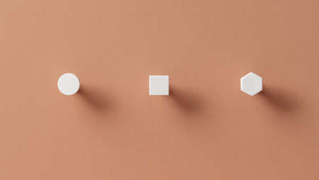Metal white hangers in forms of circle and square and hexagon on orange wall in studioの写真素材