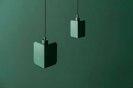 Fancy dark green metal lamps hanging on colorful background in studioの写真素材