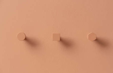 Metal orange hangers in forms of circle and square and hexagon on colorful wall in studioの写真素材