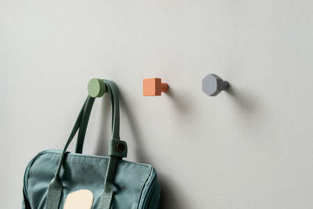 Metal multicolored geometric hangers with hanging casual bag on light wall in studioの写真素材