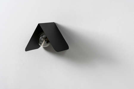 Trendy black metal lamp on gray wall in studioの写真素材