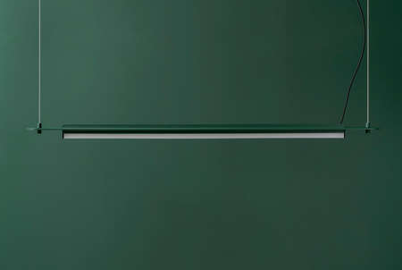 Dark green metal lamp hanging on colorful wall background in studioの写真素材