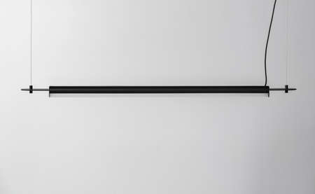 Black metal lamp hanging on gray wall background in studioの写真素材