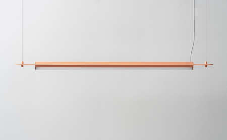 Orange metal lamp hanging on gray wall background in studioの写真素材