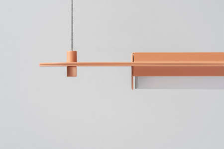 Orange metal lamp hanging on gray wall background in studioの写真素材