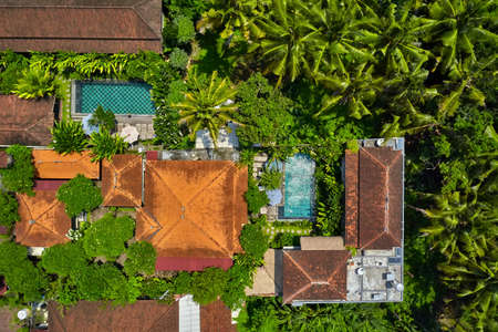 Villas with colorful shingle roofs and swimming pools between palm treesの写真素材