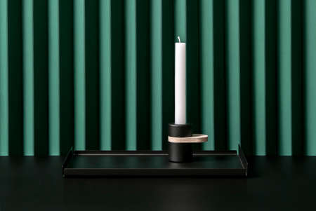 Trendy metal black tray with dark candlestick on folded green wall backgroundの写真素材