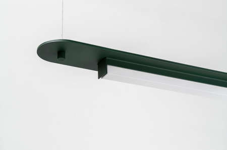 Dark green metal lamp hanging on gray wall background in studioの写真素材
