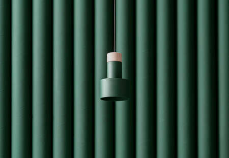 Dark green metal-wooden lamp hanging on folded colorful wall background in studioの写真素材