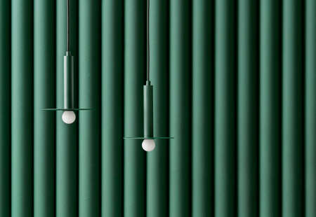 Dark green metal lamps hanging on folded colorful wall background in studioの写真素材
