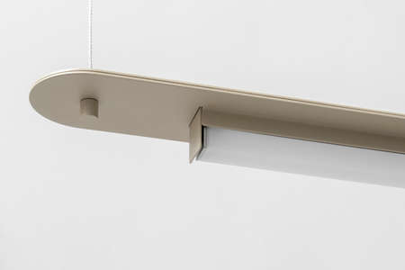 Wonderful metal beige LED lamp is hanging on the gray wall background indoors. Closeup horizontal photo.の写真素材